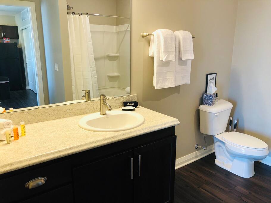 A clean bathroom with a shower tub combo, toilet, and vanity with mirror in a furnished apartment in Downton Columbus