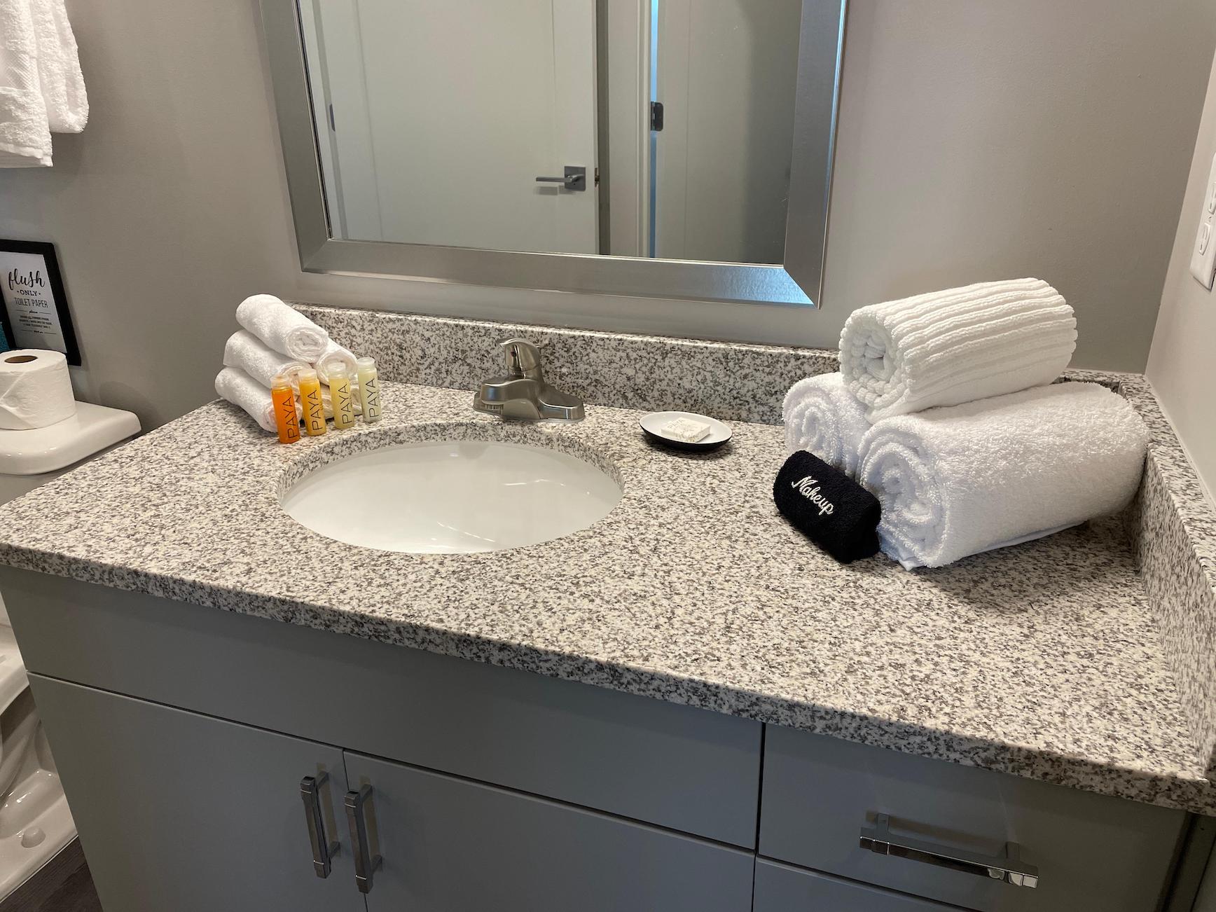 Kitchen sink and vanity with towels and toiletries in a furnished apartment near Ohio State