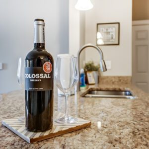 A bottle of wine and two clean wine glasses on the kitchen counter of a furnished apartment in Westerville Ohio