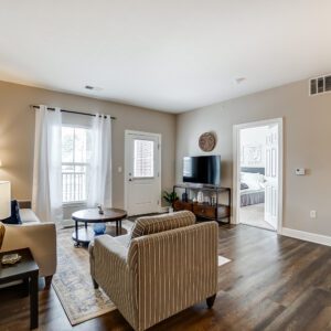 Living room with a smart tv, coffee table, and a door to the patio in a furnished apartment in Westerville Ohio