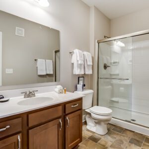 A clean bathroom with a shower tub combo, toilet, and vanity with mirror in a furnished apartment in Westerville Ohio