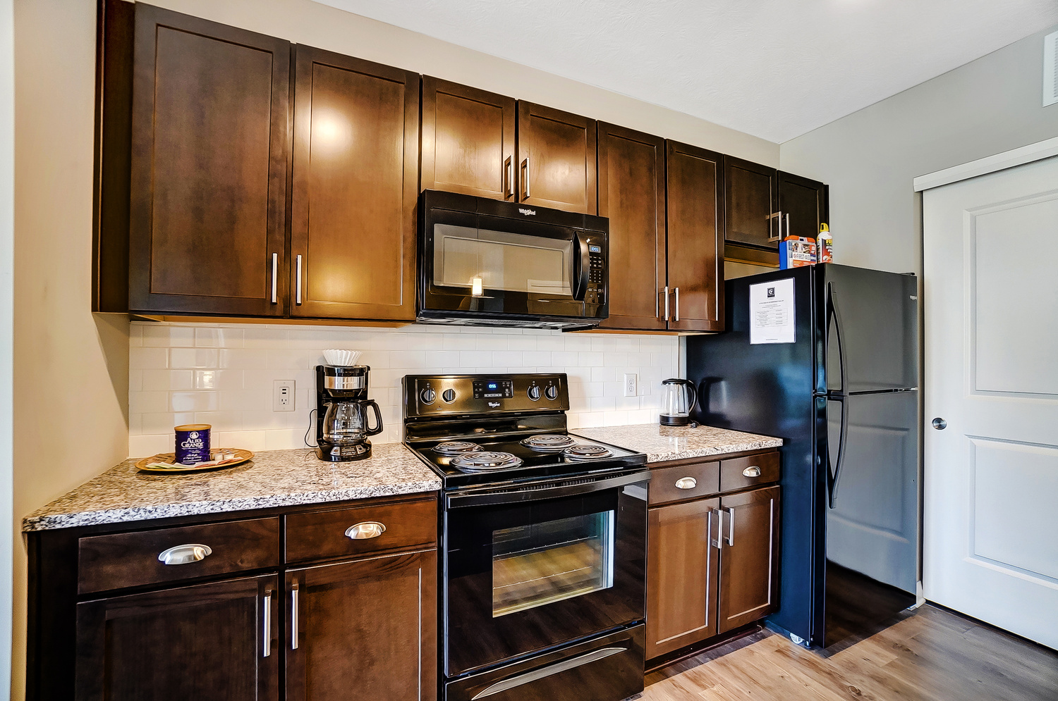 A kitchen with brown cabinets and black appliances in a furnished apartment in Downtown Columbus