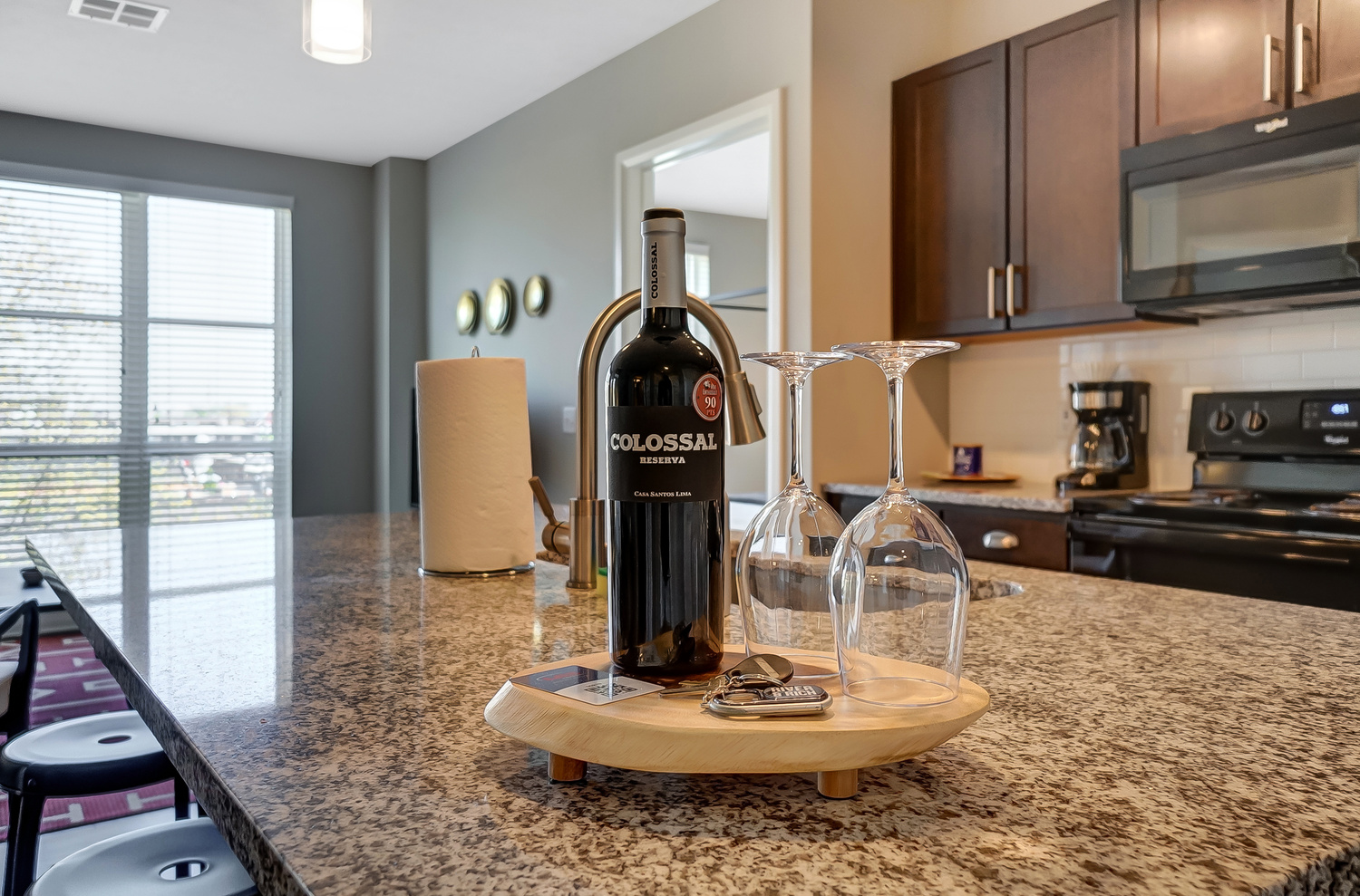 A bottle of wine and two clean wine glasses on the kitchen counter of a furnished apartment in Downtown Columbus