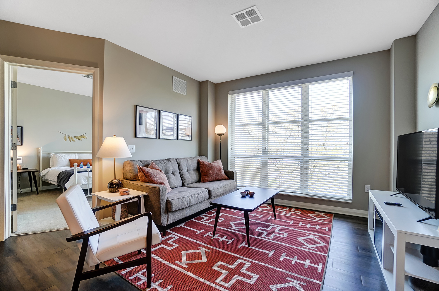 Living room with couch, coffee table, side chair, and large windows in a furnished apartment in Downtown Columbus