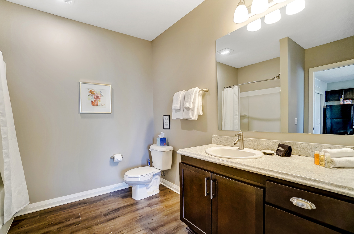 A clean bathroom with a shower tub combo, toilet, and vanity with mirror in a furnished apartment in Downton Columbus