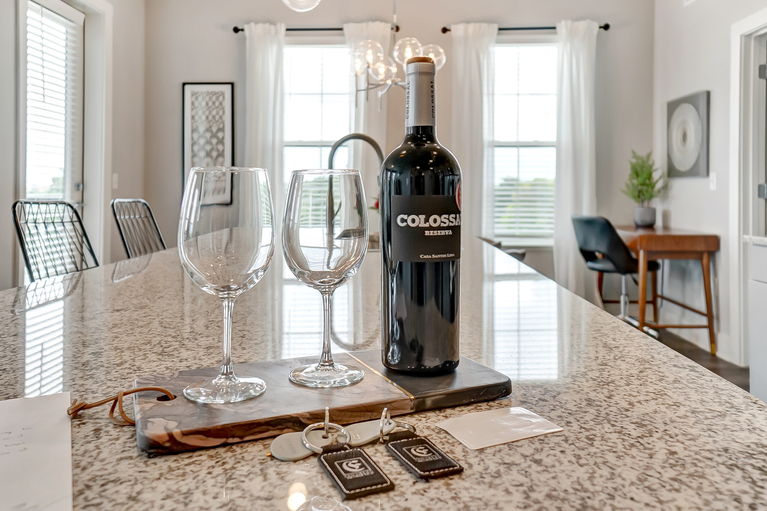 A bottle of wine and two clean wine glasses on the kitchen counter of a furnished apartment near OSU