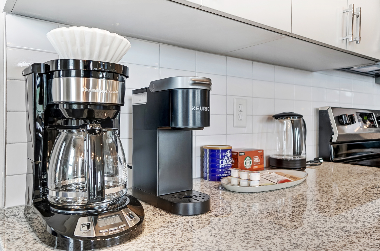 A coffee maker, a Keurig, k-cups, and Alto Grande coffee on the kitchen counter of a furnished apartment near OSU