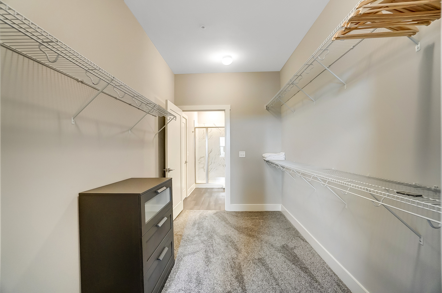 Large closet with a dresser that connects to both a bedroom and a bathroom in a furnished apartment near OSU