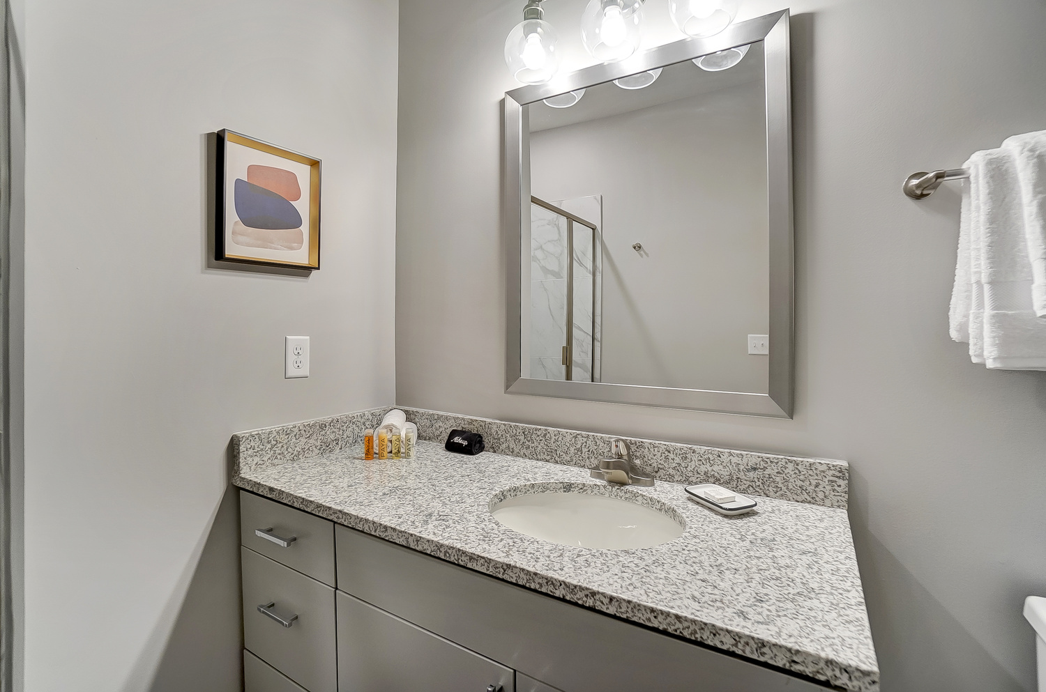 Bathroom sink and vanity with a mirror and art on the wall in a furnished apartment near OSU