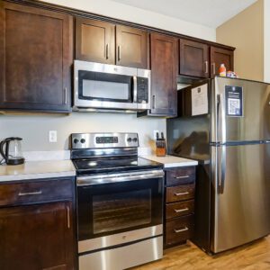 A kitchen with brown cabinets and stainless steel appliances in a furnished apartment in Hilliard Ohio