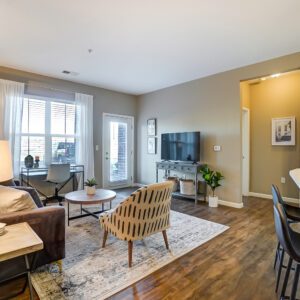 Living room with couch, coffee table, side chair, Smart TV, and large windows in a furnished apartment in Hilliard Ohio