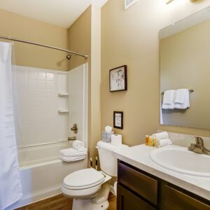 A clean bathroom with a shower tub combo, toilet, and vanity with mirror in a furnished apartment in Hilliard Ohio