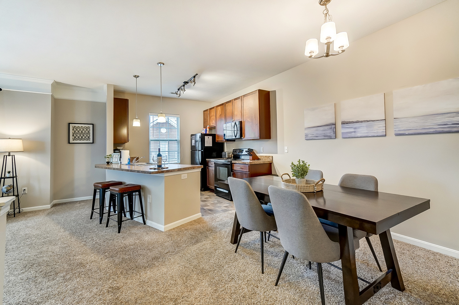 A dining table with chairs and a kitchen space in a furnished apartment near New Albany Ohio