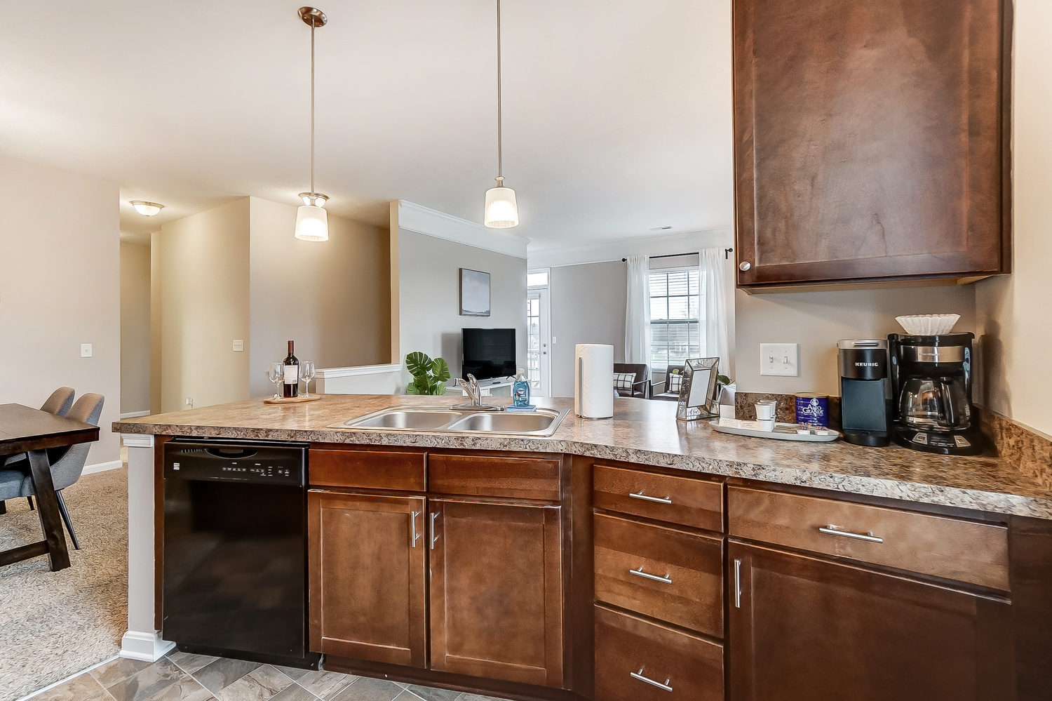 A kitchen with a sink and a dishwasher in a furnished apartment near New Albany Ohio