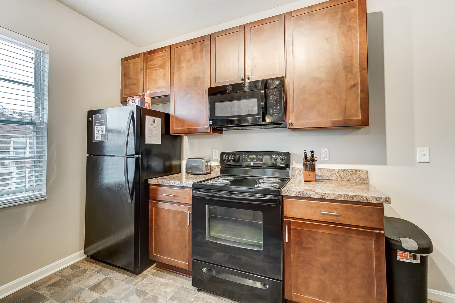 A refrigerator, oven, and microwave in the kitchen of a furnished apartment near New Albany Ohio