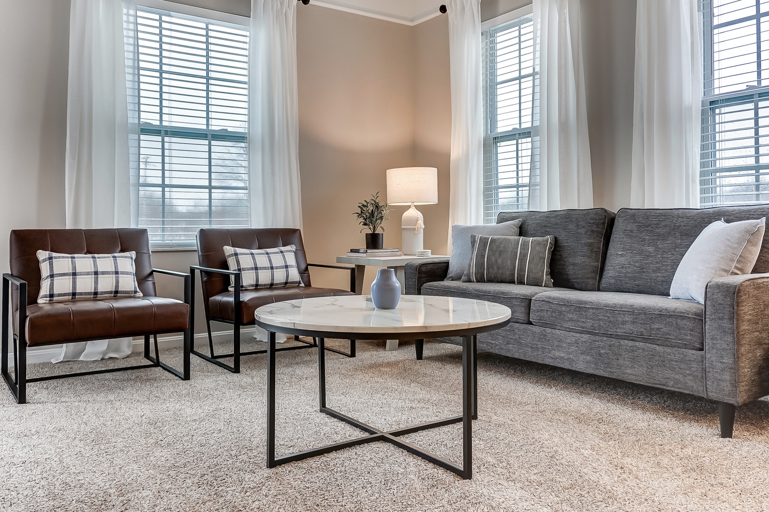 A living room with a couch, a coffee table, a lamp, and chairs in a furnished apartment near New Albany Ohio