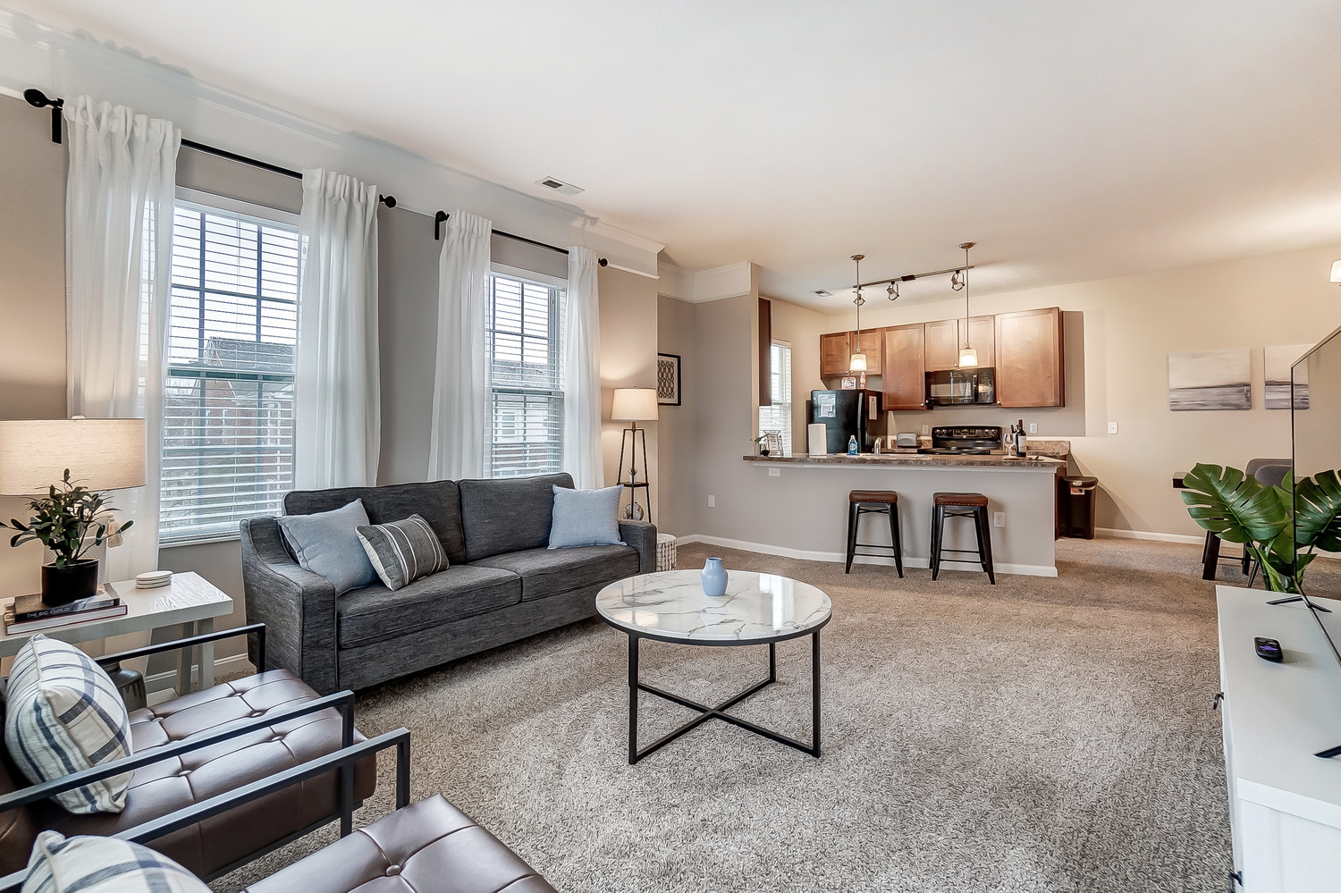 Living room with couch, coffee table, and chairs in a furnished apartment near New Albany Ohio