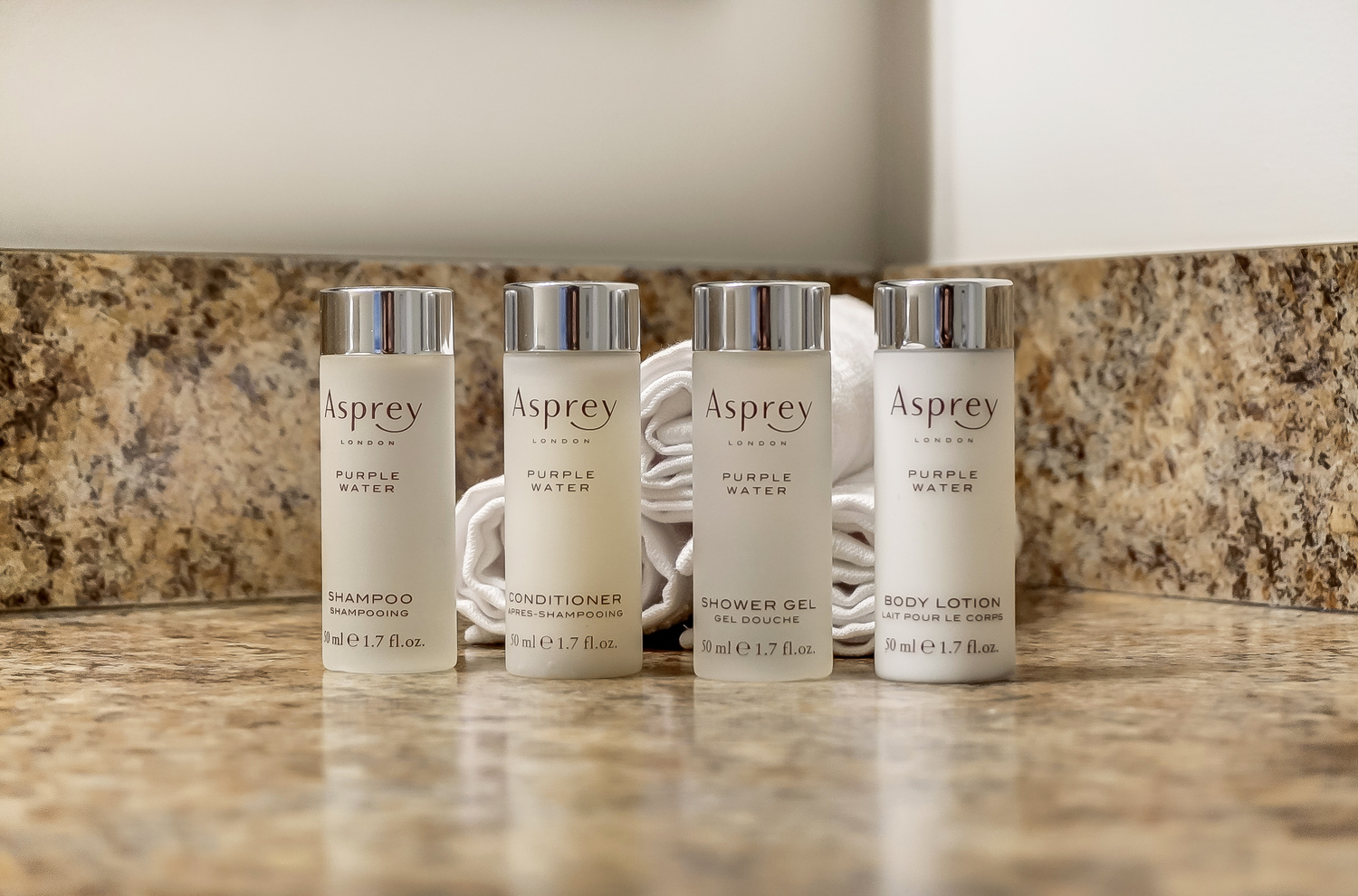 Asprey toiletries lined up in front of rolled washcloths on the bathroom vanity of a furnished apartment in New Albany Ohio