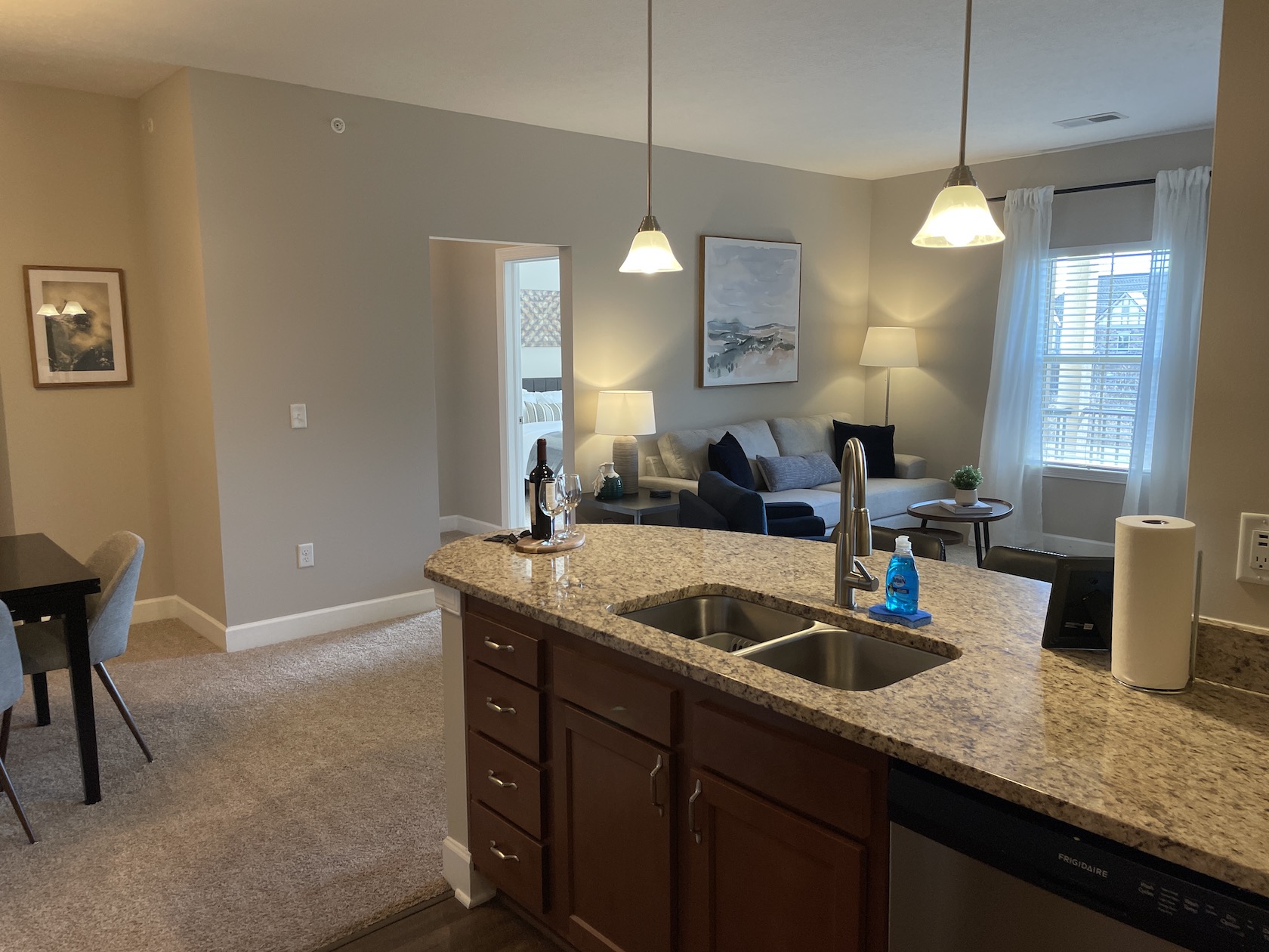 A kitchen counter with a sink and stainless steel dishwasher in a furnished apartment in Westerville Ohio