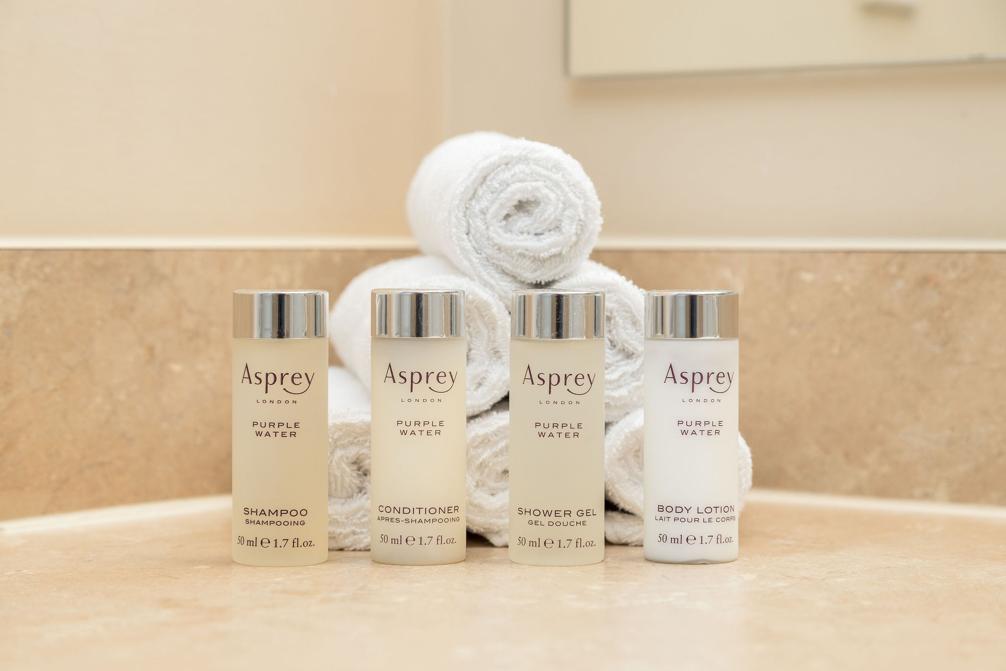 Asprey toiletries lined up in front of rolled washcloths on the bathroom vanity of a furnished apartment in New Albany Ohio