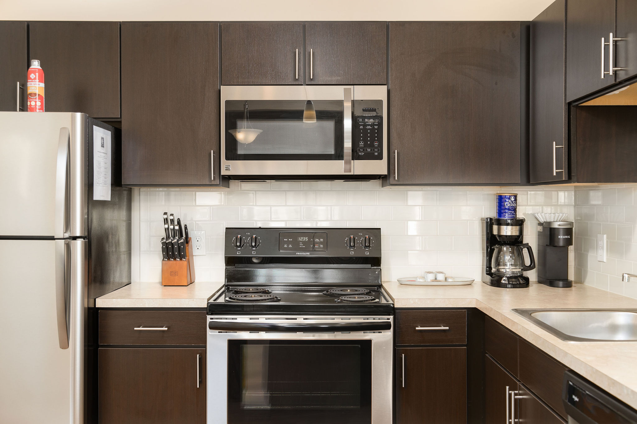 A kitchen with brown cabinets and stainless steel appliances in a furnished apartment near New Albany Ohio