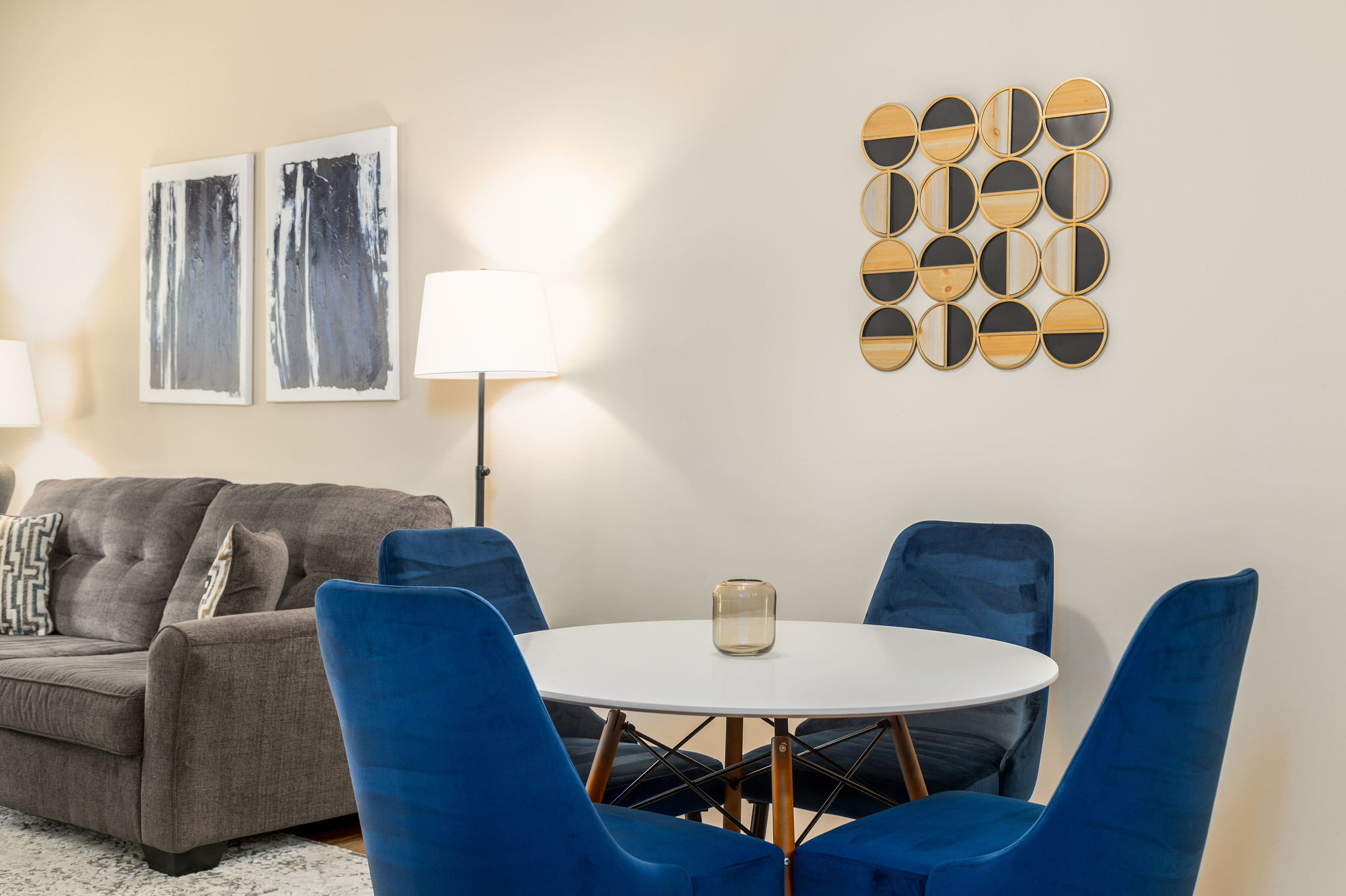 A dining area with a dining table with four blue chairs and wall art in a furnished apartment near New Albany Ohio