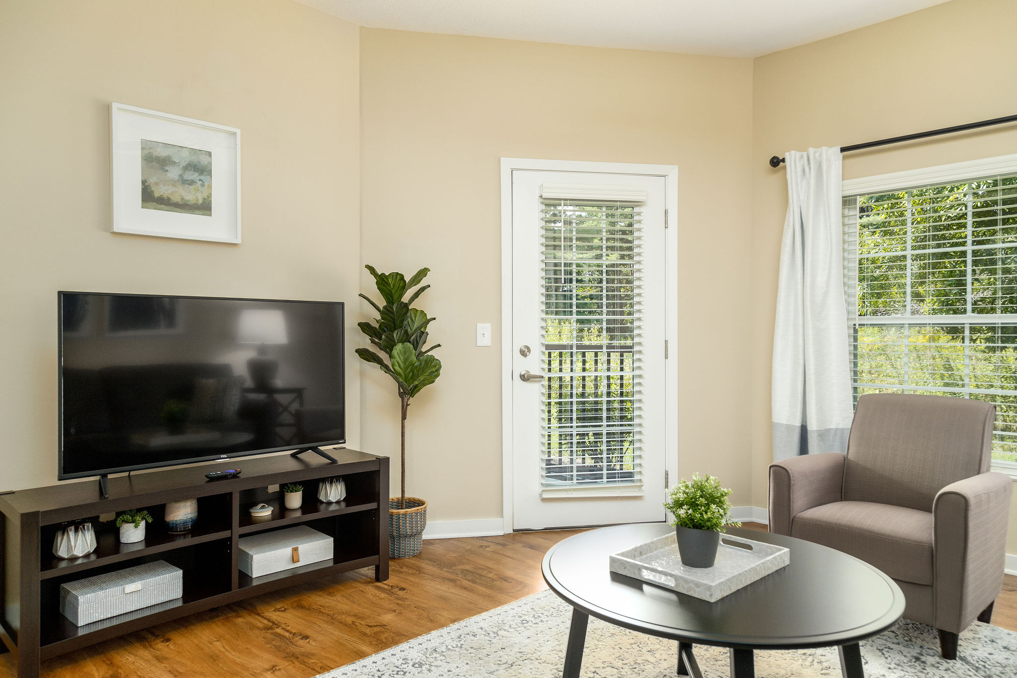 Living room with a smart tv, coffee table, and a door to the patio in a furnished apartment near New Albany Ohio