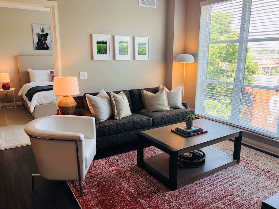 Living room with couch, coffee table, side chair, and large windows in a furnished apartment in Downtown Columbus