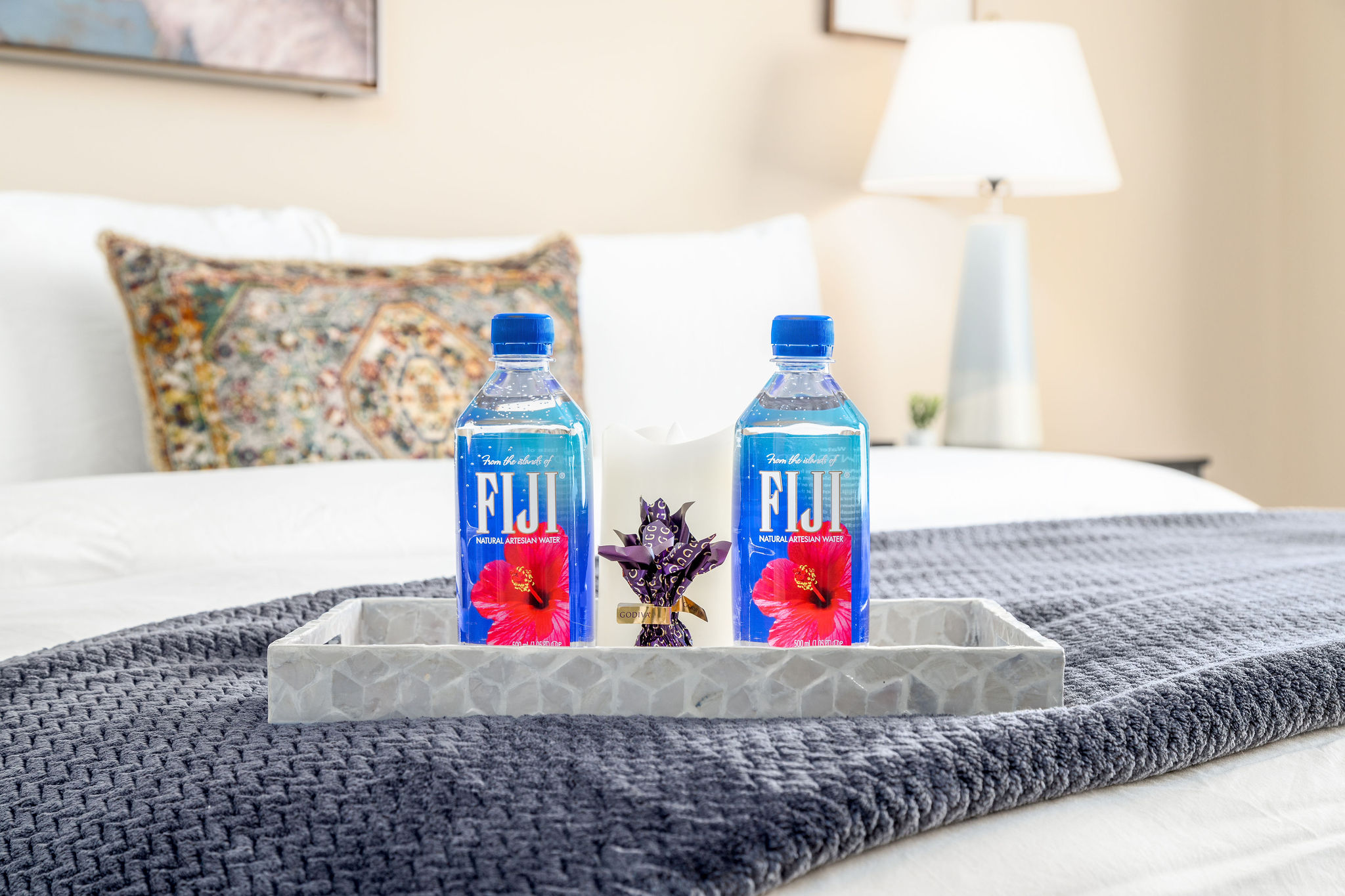 Fiji waters, chocolates, and a candle on a bed tray in a furnished apartment near New Albany Ohio