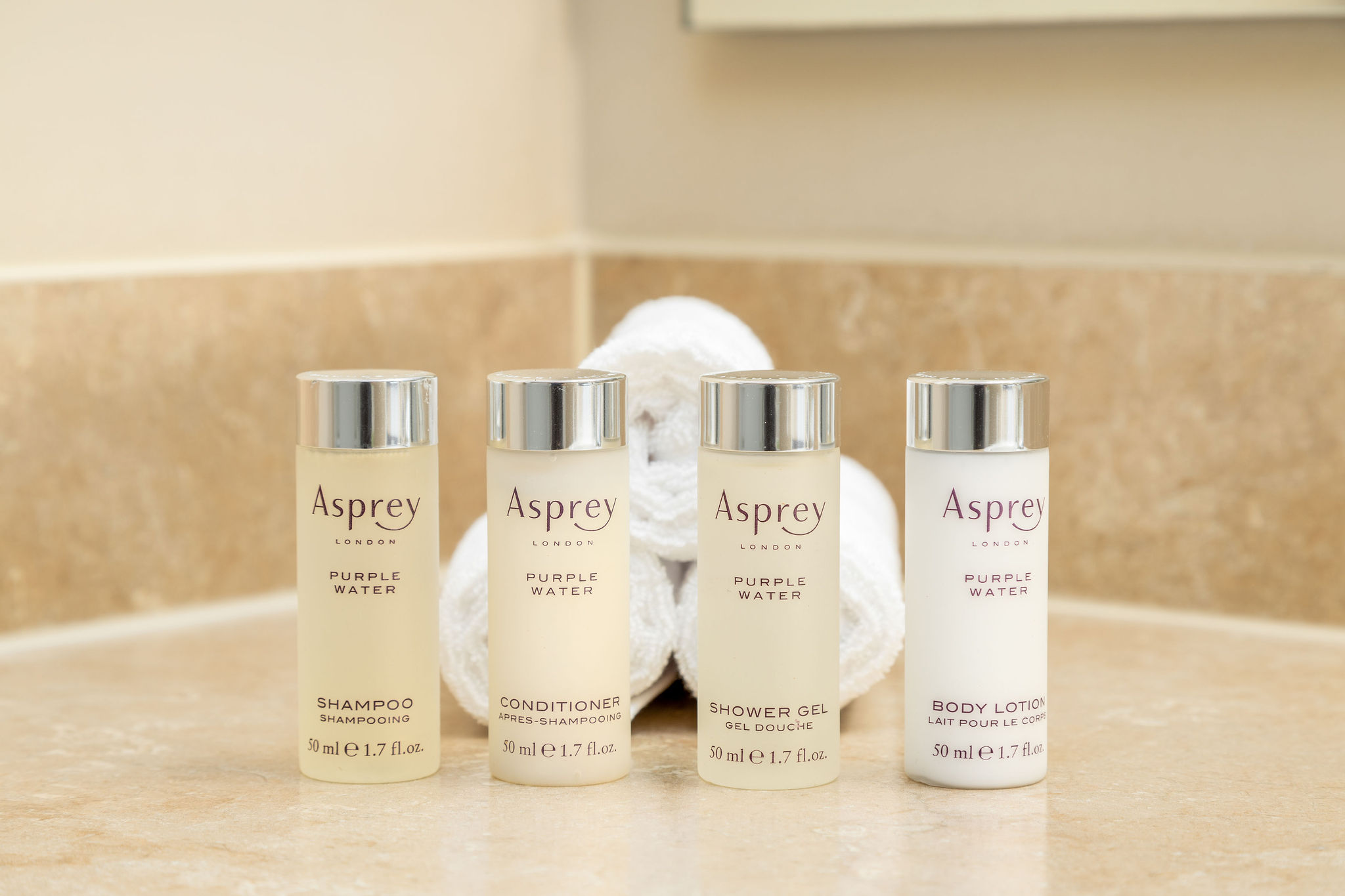 Asprey toiletries lined up in front of rolled washcloths on the bathroom vanity of a furnished apartment in New Albany Ohio