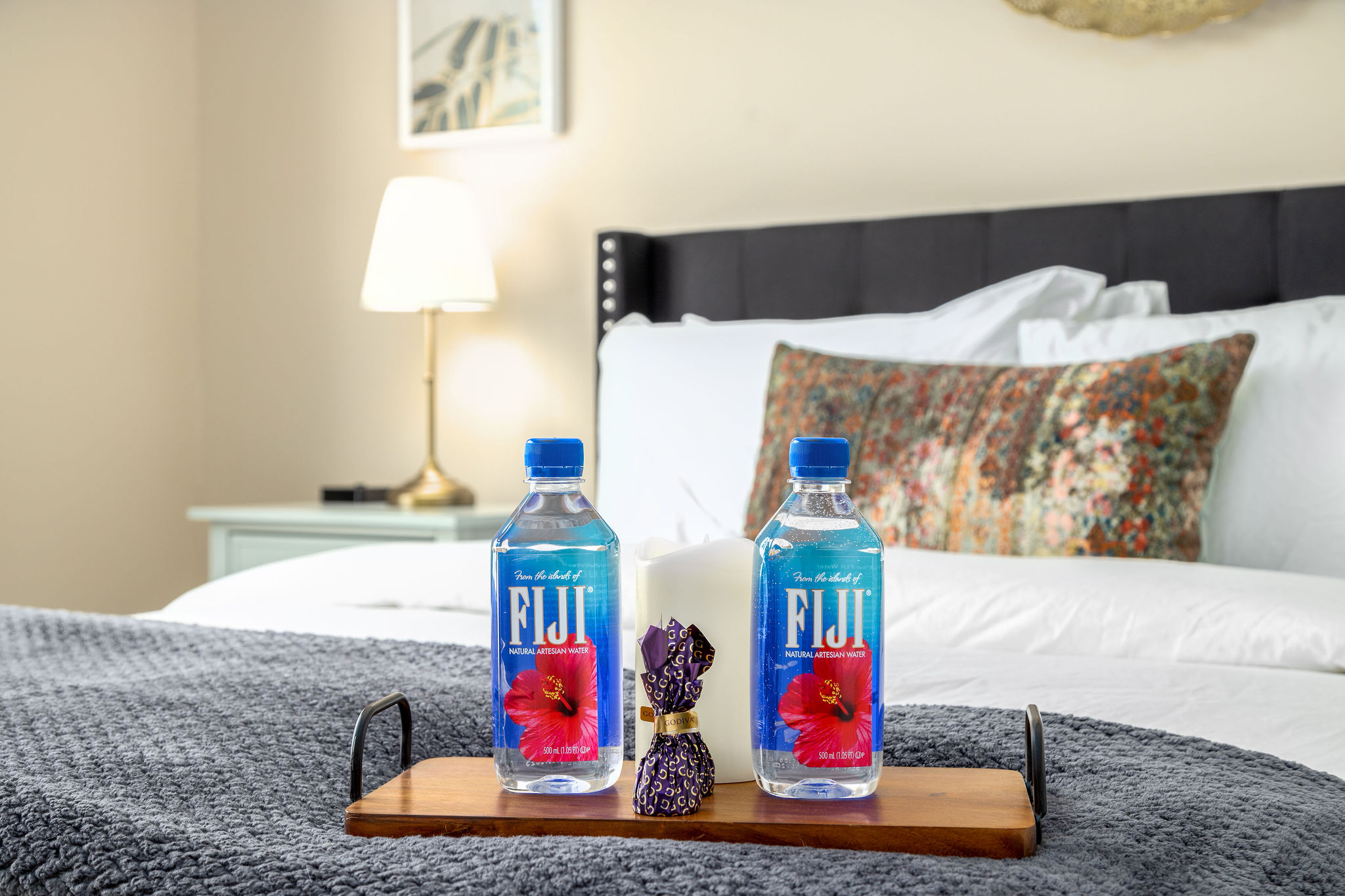 Fiji waters, chocolates, and a candle on a bed tray in a furnished apartment near New Albany Ohio