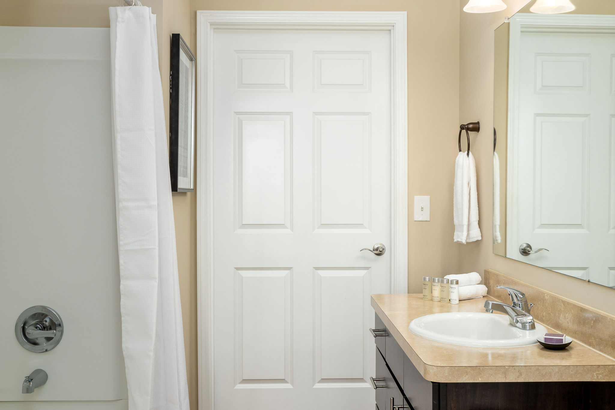 A bathroom with towels and a shower curtain in a furnished apartment near New Albany Ohio