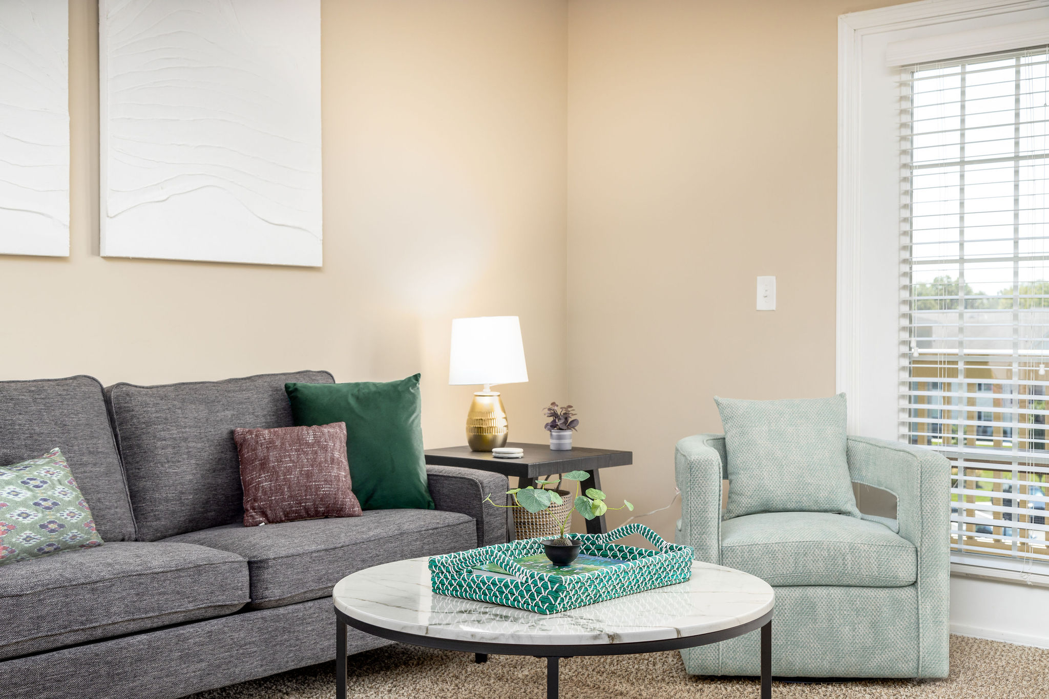 A living room with a couch, a coffee table, a lamp, and a chair in a furnished apartment near New Albany Ohio