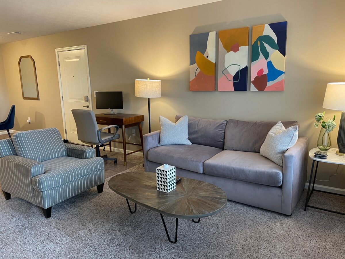 Living room with couch, coffee table, desk, and chairs in a furnished apartment in Dublin Ohio