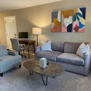 Living room with couch, coffee table, desk, and chairs in a furnished apartment in Hilliard Ohio