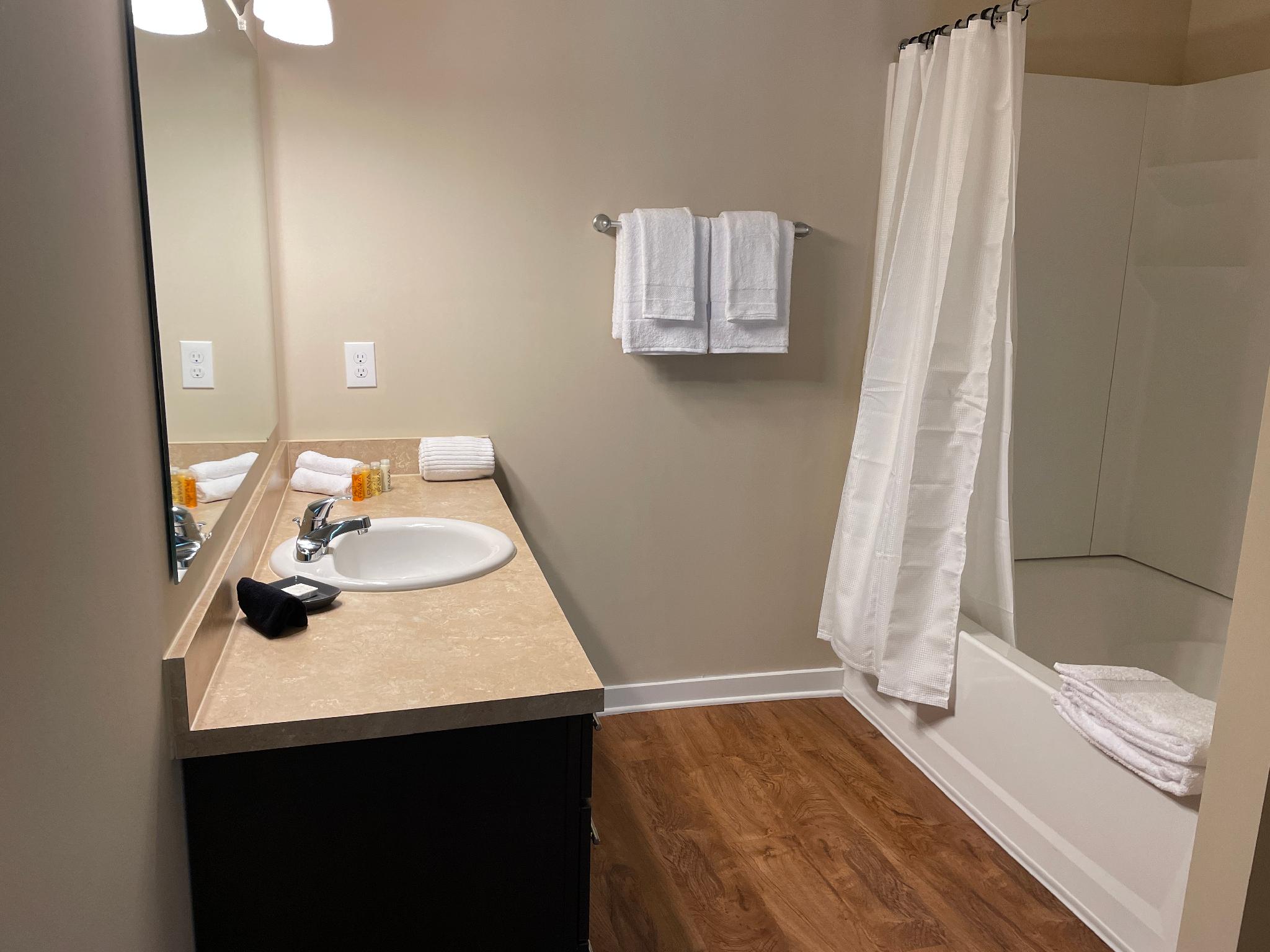 A bathroom vanity with a mirror and a shower tub combo in a furnished apartment near New Albany Ohio