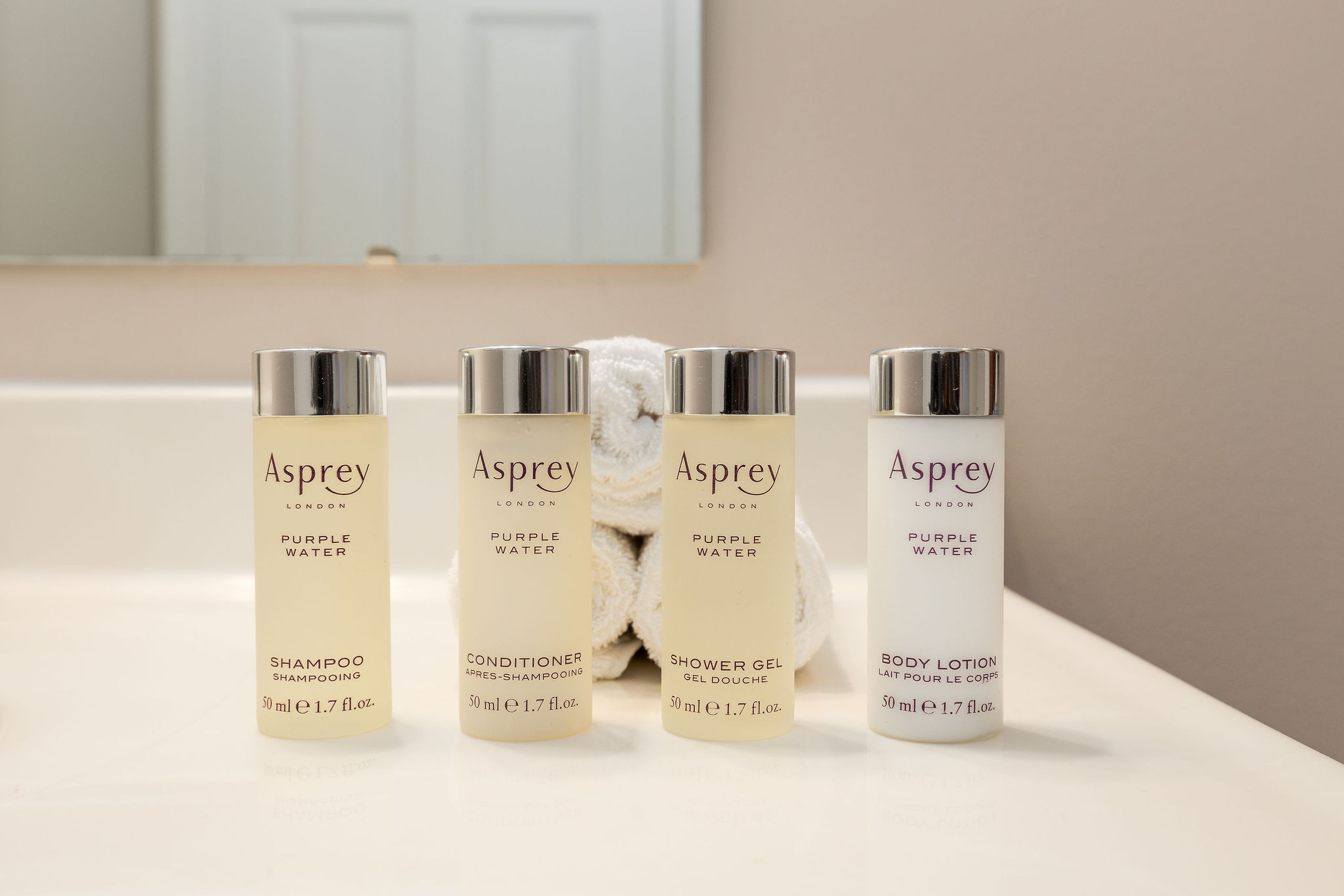 Asprey toiletries lined up on the bathroom vanity in front of clean white washcloths in a furnished apartment in Westerville Ohio