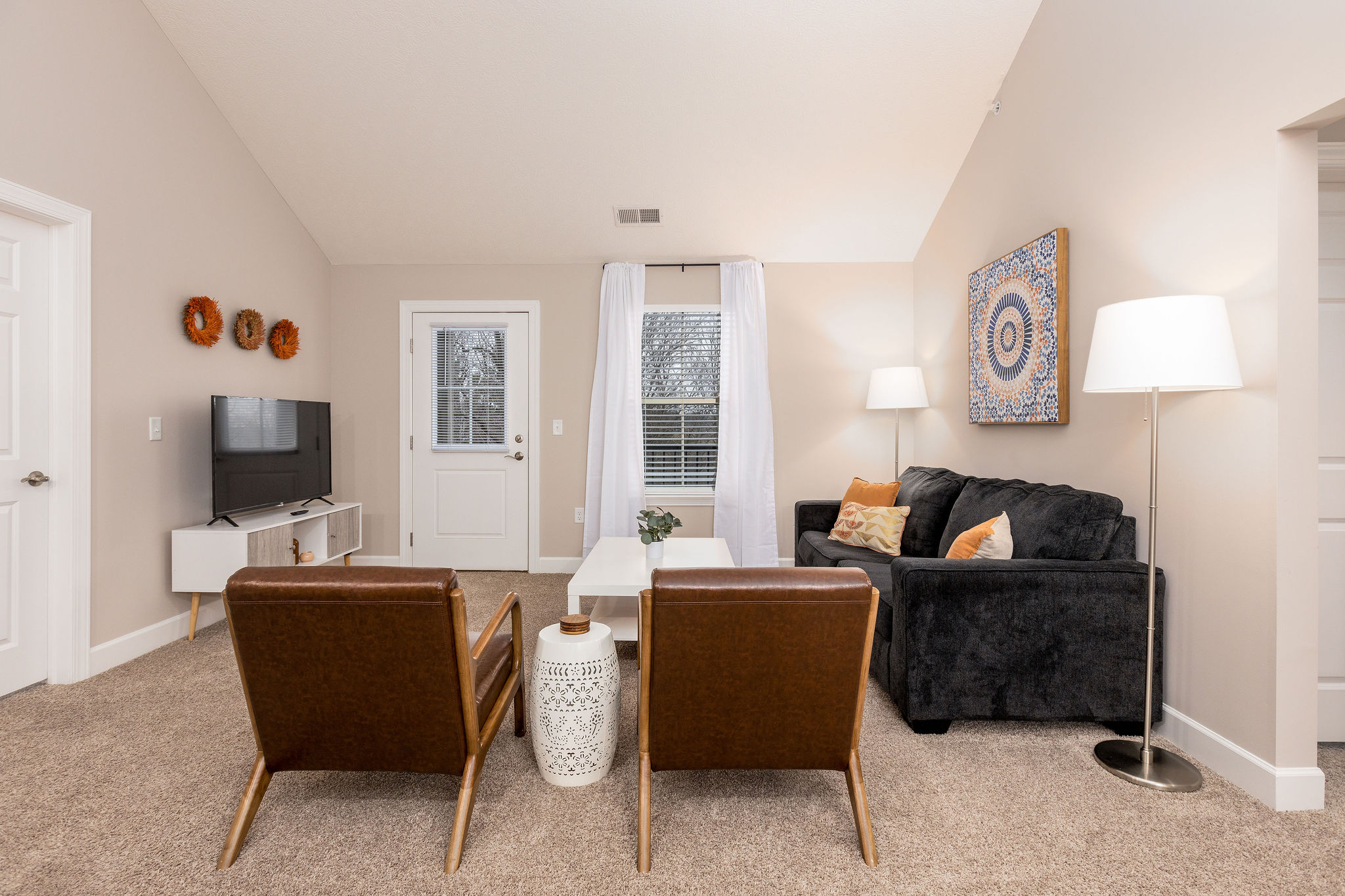 Living room with a smart tv, coffee table, and a door to the balcony in a furnished apartment in Westerville Ohio