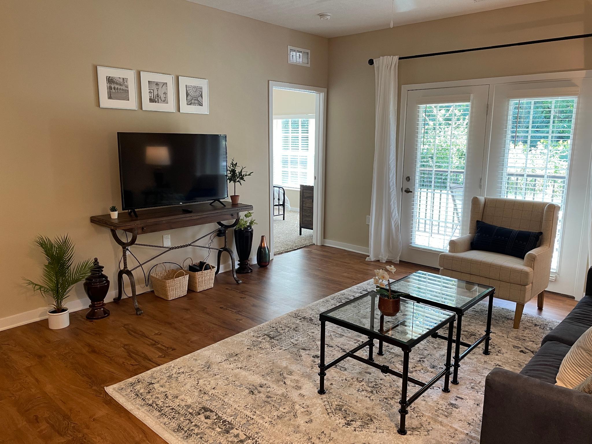 Living room with a smart tv, coffee table, and a door to the patio in a furnished apartment near New Albany Ohio