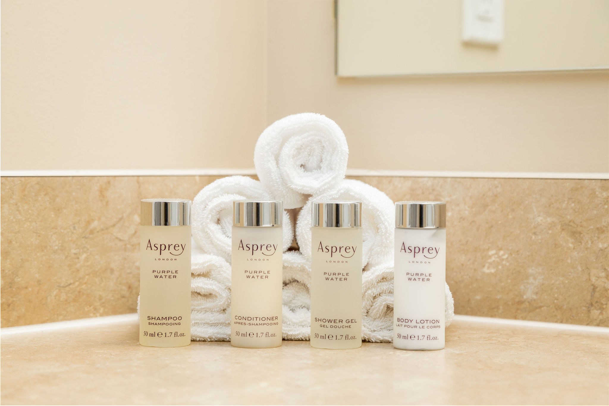 Asprey toiletries lined up in front of rolled washcloths on the bathroom vanity of a furnished apartment in New Albany Ohio