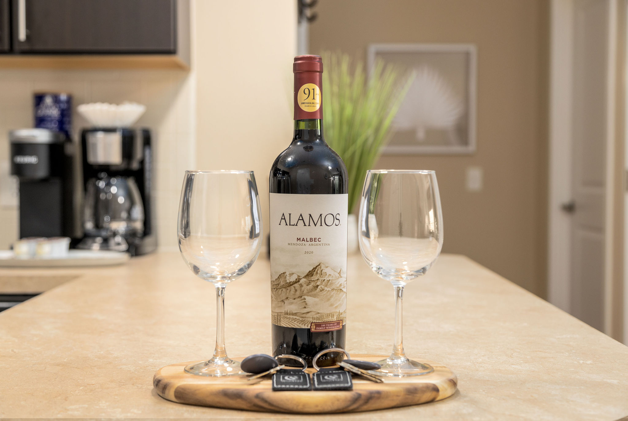 A bottle of wine and two clean wine glasses on the kitchen counter of a furnished apartment near New Albany Ohio