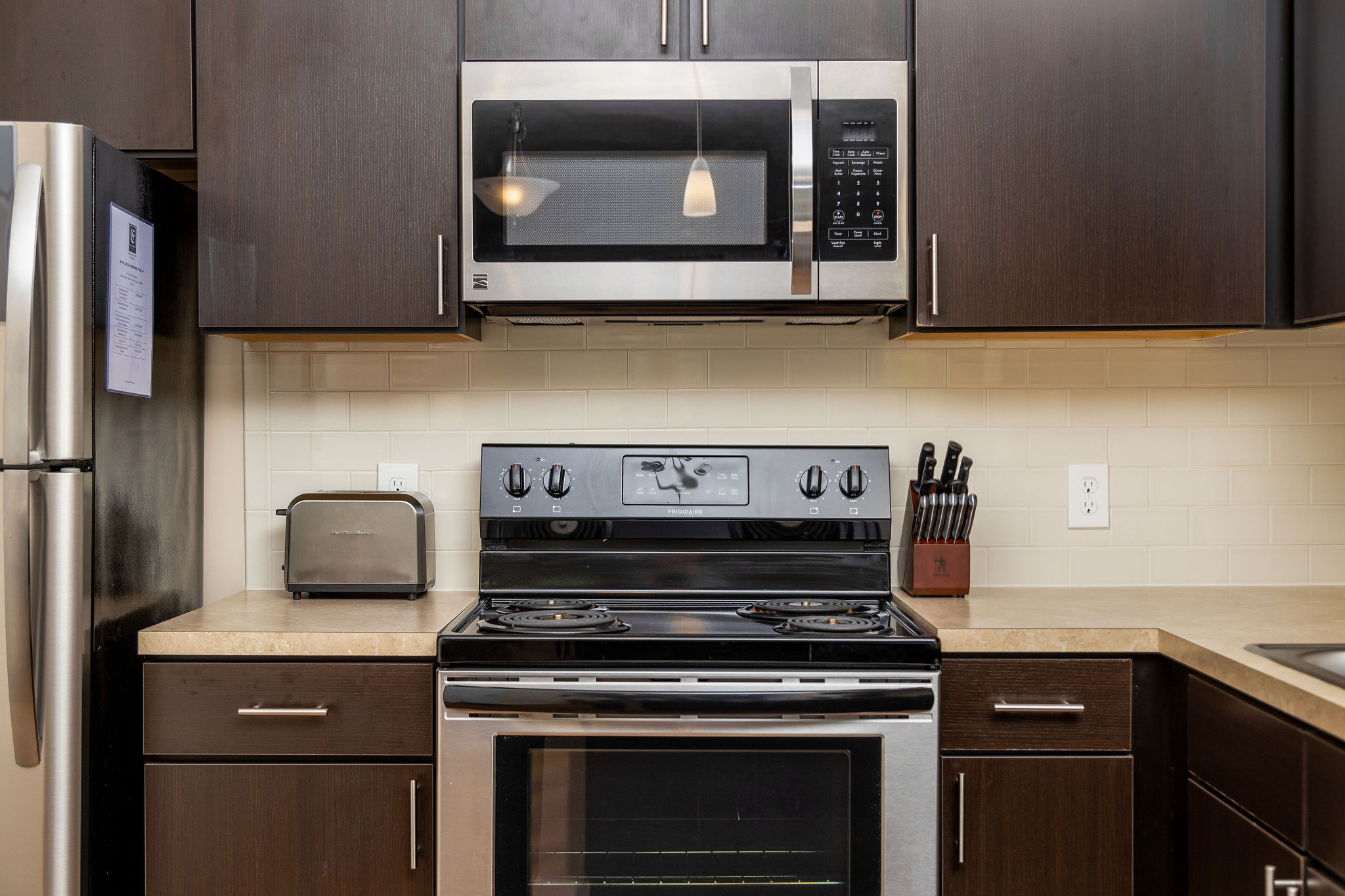 A kitchen with brown cabinets and stainless steel appliances in a furnished apartment near New Albany Ohio