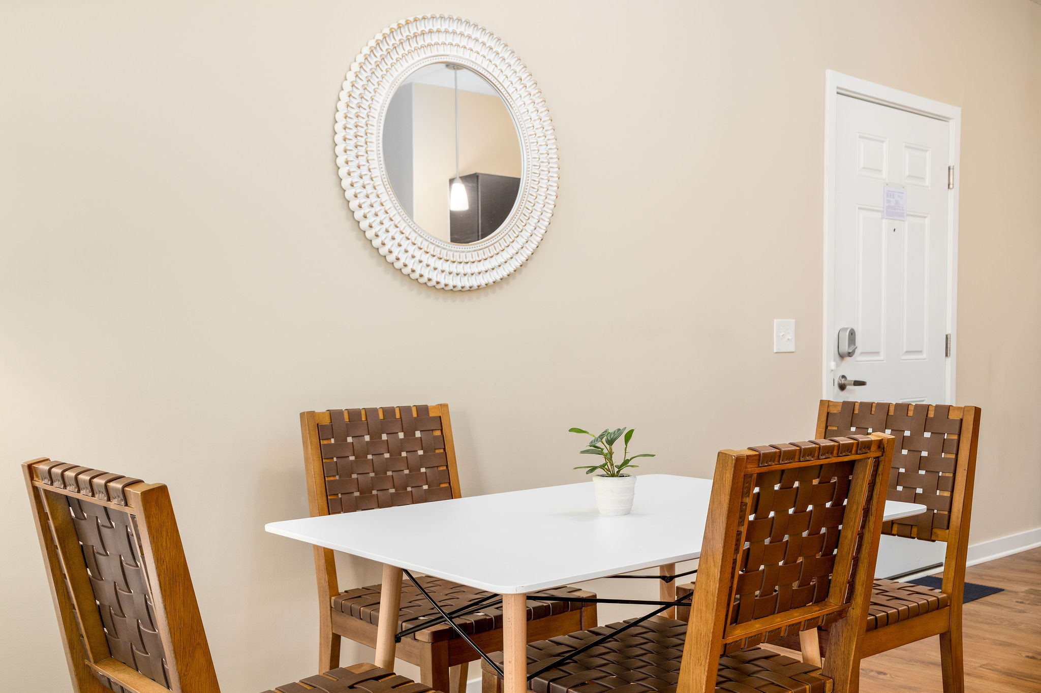 A dining area with a dining table with four chairs and a wall mirror in a furnished apartment near New Albany Ohio