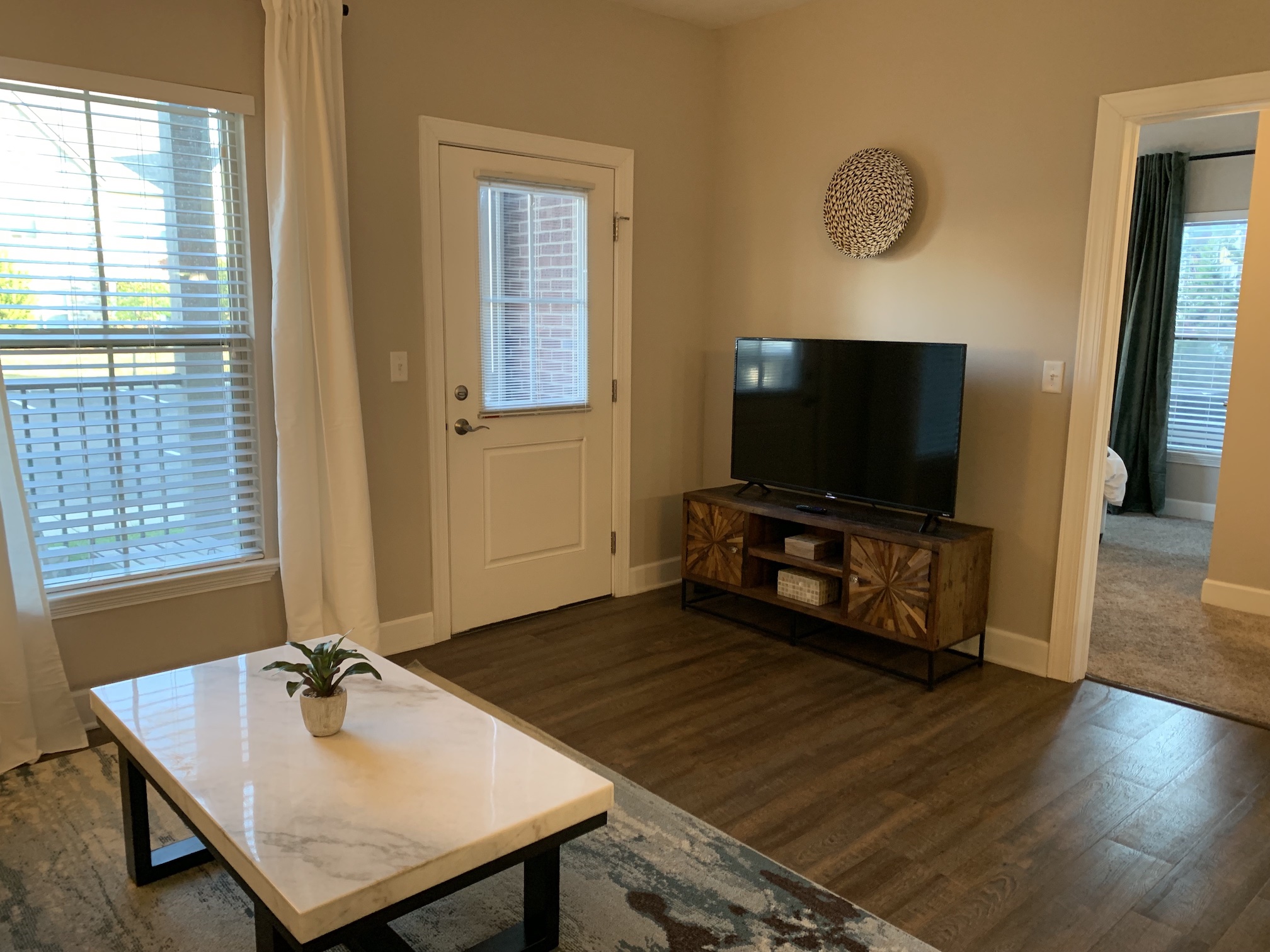 Living room with a smart tv, coffee table, and a door to the patio in a furnished apartment in Westerville Ohio