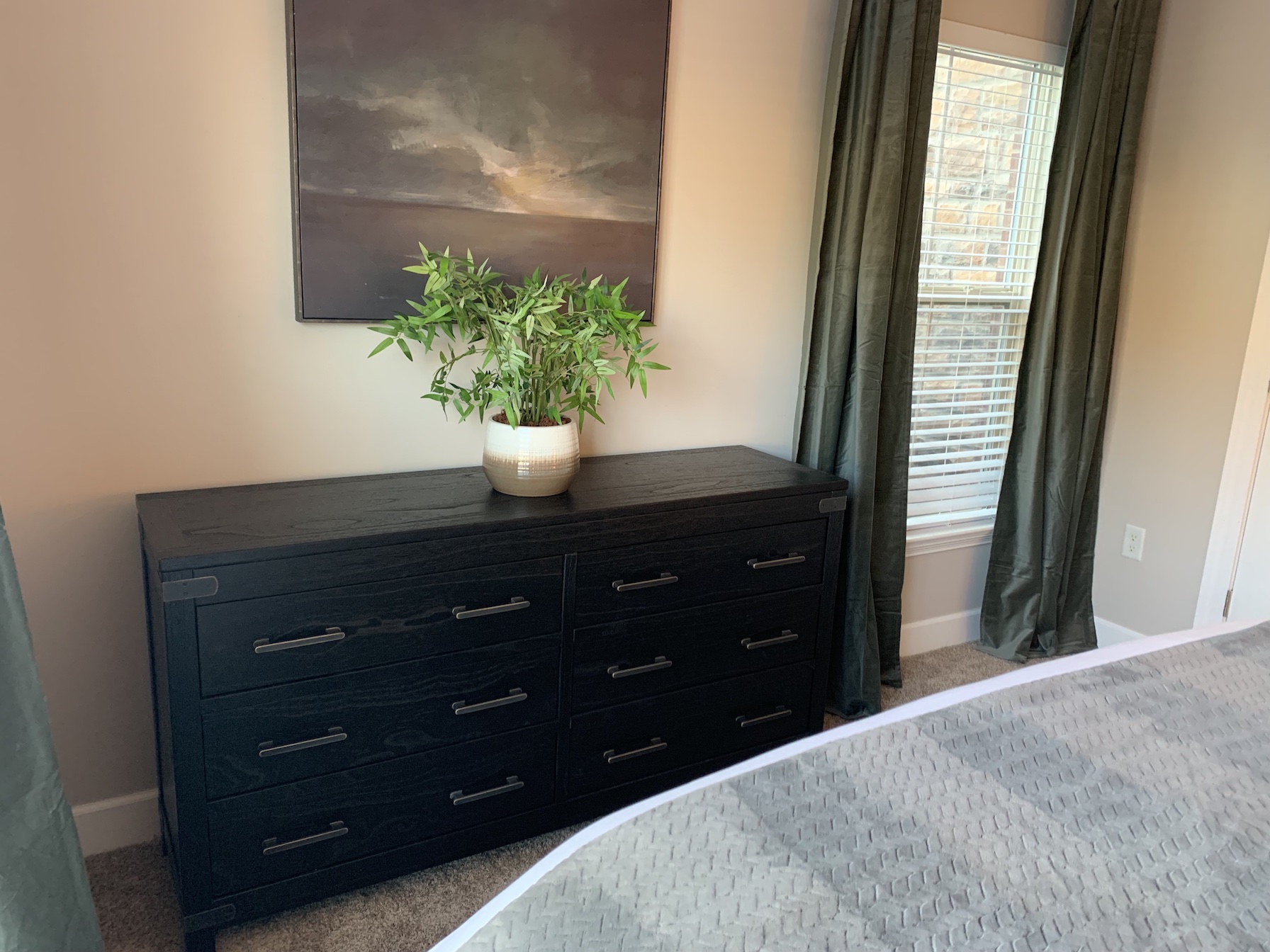 A black dresser and wall art in the bedroom of a furnished apartment in Westerville Ohio