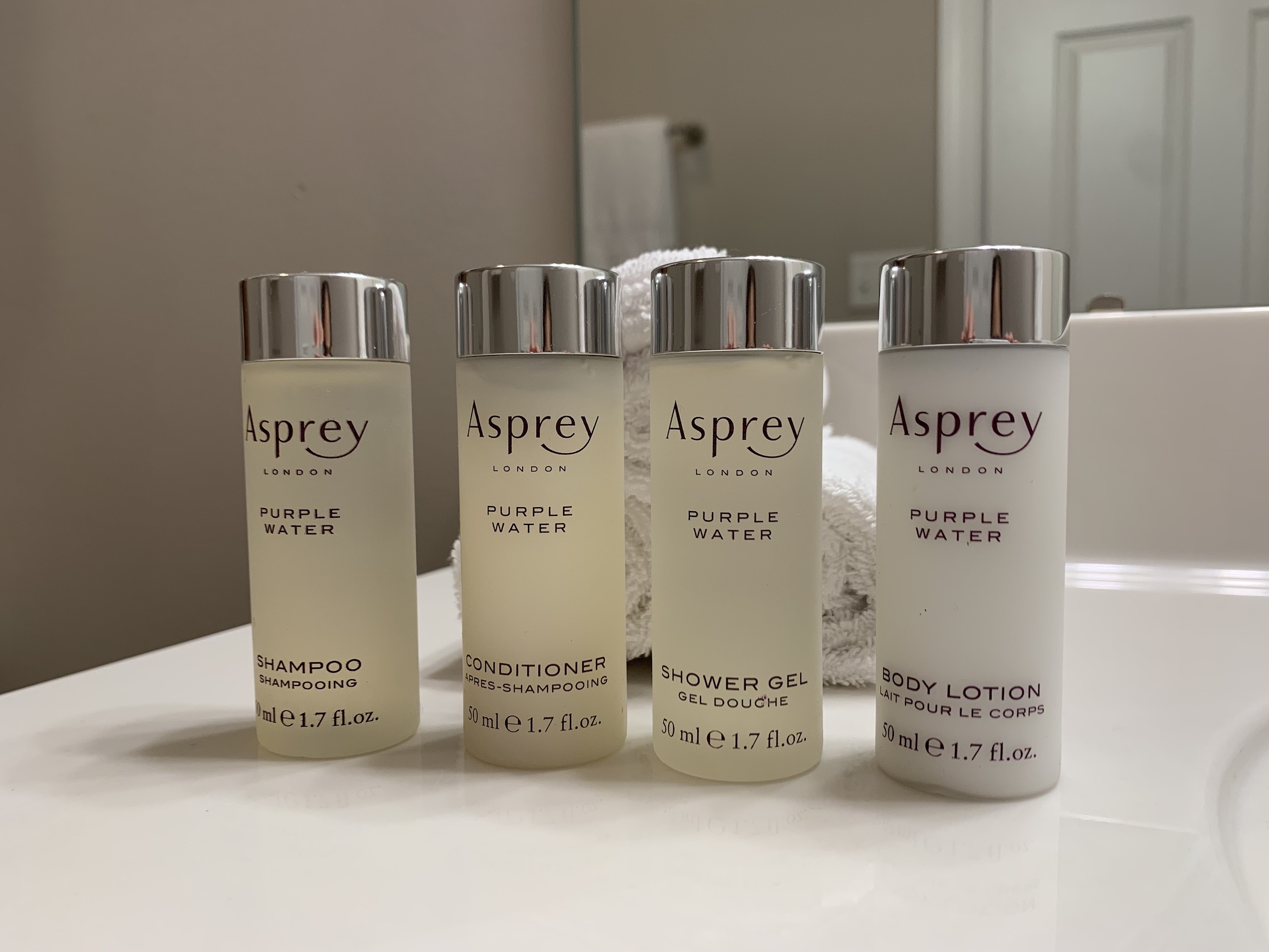 Asprey toiletries lined up on the bathroom vanity in front of clean white washcloths in a furnished apartment in Westerville Ohio