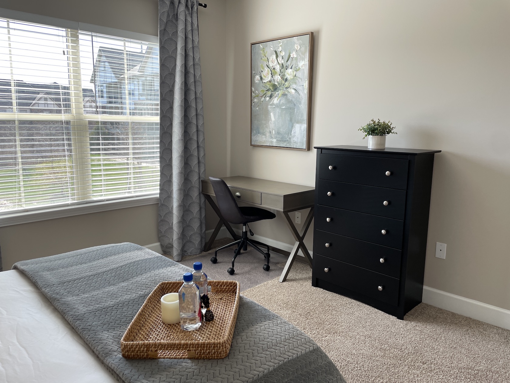 A bedroom with a queen bed, a chest of drawers, and desk with desk chair in a furnished apartment in Westerville Ohio