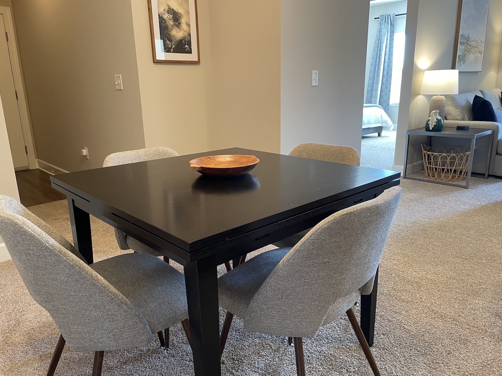 A dining area with a dining table, four chairs, and wall art in a furnished apartment near Westerville Ohio