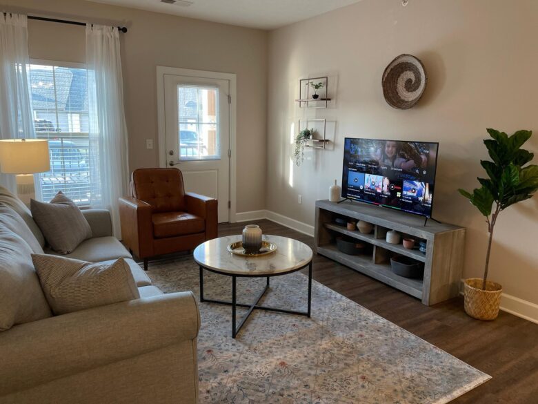 Living room with a smart tv, coffee table, couch, chair, and a door to the patio in a furnished apartment in Westerville Ohio