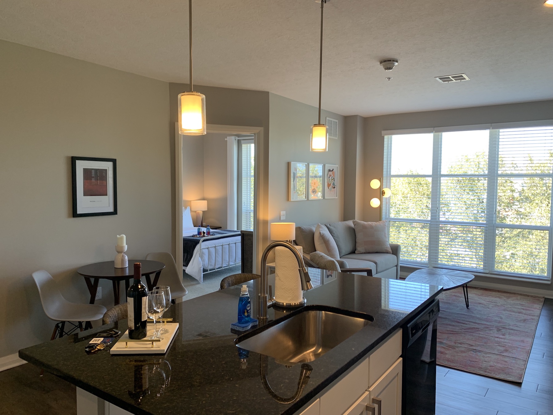 A kitchen island with a sink, dishwasher, and microwave in a furnished apartment in Downtown Columbus